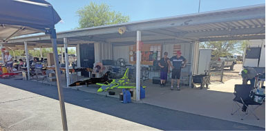 Covered outdoor area with people, tables, and model planes.