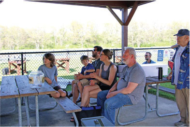 People sitting under a pavilion, engaged in conversation.
