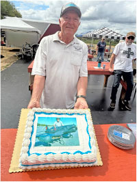 Man holding a cake with a photo of a plane on it.