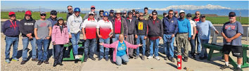 Group photo of people outdoors, mountains in the background, sunny day.