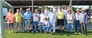 Group of people posing outdoors, some wearing hats and casual clothing.