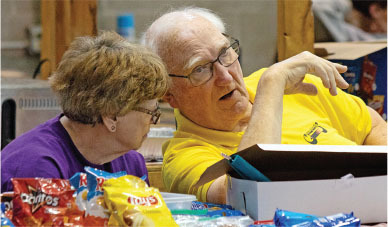Two people converse at a table with snack bags, in a casual setting.