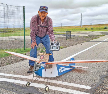 Man smiling with a remote-controlled airplane at an air