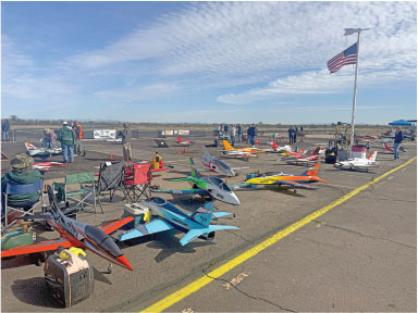 Model airplanes lined up on an airfield, with an American flag flying overhead.