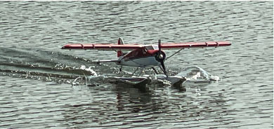 Seaplane with red wings landing on the water.