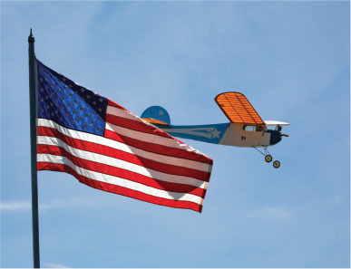 American flag and vintage plane against a clear blue sky.