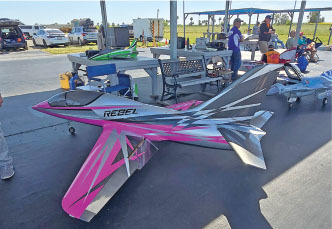 Model jet with pink and gray design labeled "Rebel" on a table outdoors.