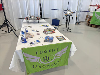 Model airplanes on a table with "Eugene RC Aeronauts" banner.