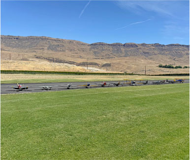 Model airplanes on a grassy field with hills in the background.