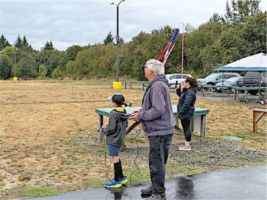 People controlling model planes at an outdoor field on a cloudy day.