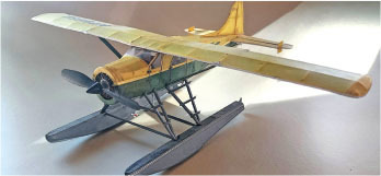 Yellow and green model seaplane on a table, lit from above.