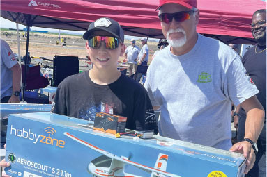 Teen and older man smiling, holding a Hobby Zone Aeroscout 2.1m box.