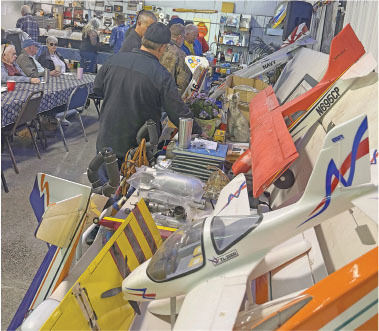 Model airplanes displayed indoors with people gathered at tables.