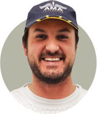 Smiling man wearing a navy cap with "AMA" text.