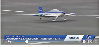 Small blue and white RC plane on runway with news text overlay.