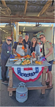 Group around table with hot dogs, decorated in patriotic colors.