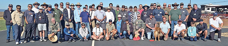 A large group of people posing outdoors on a sunny day.