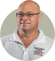 Man with glasses in white AMA polo shirt, neutral background.