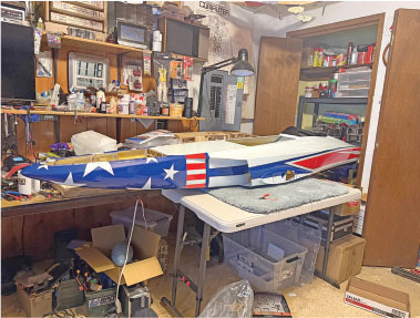 Model jet with American flag design on a workshop table surrounded by tools.
