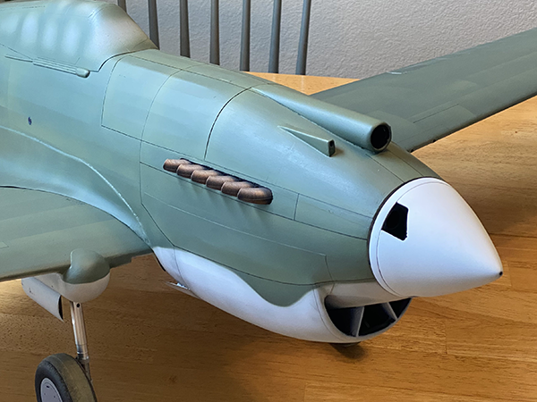 Model airplane with green body on a wooden table.