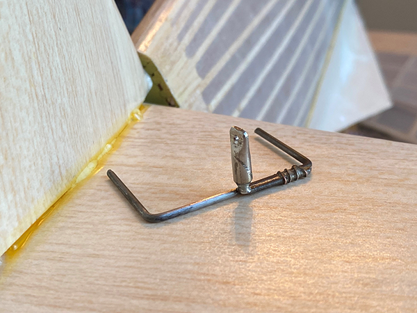 Small metal bracket screwed into wood.