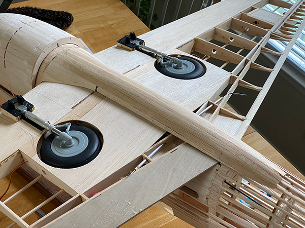 Wooden model airplane with landing gear on a table.