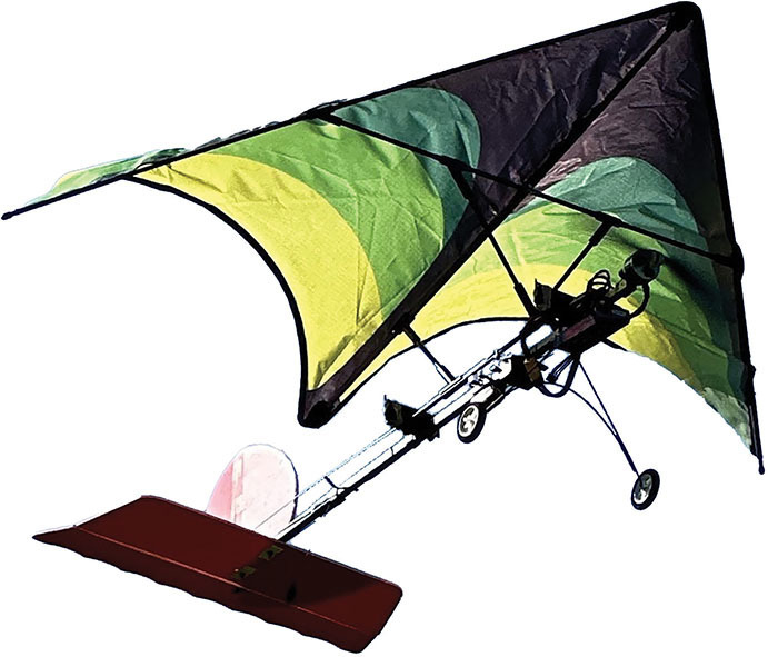 Hang glider with green and black wings, red tail, and wheeled base.