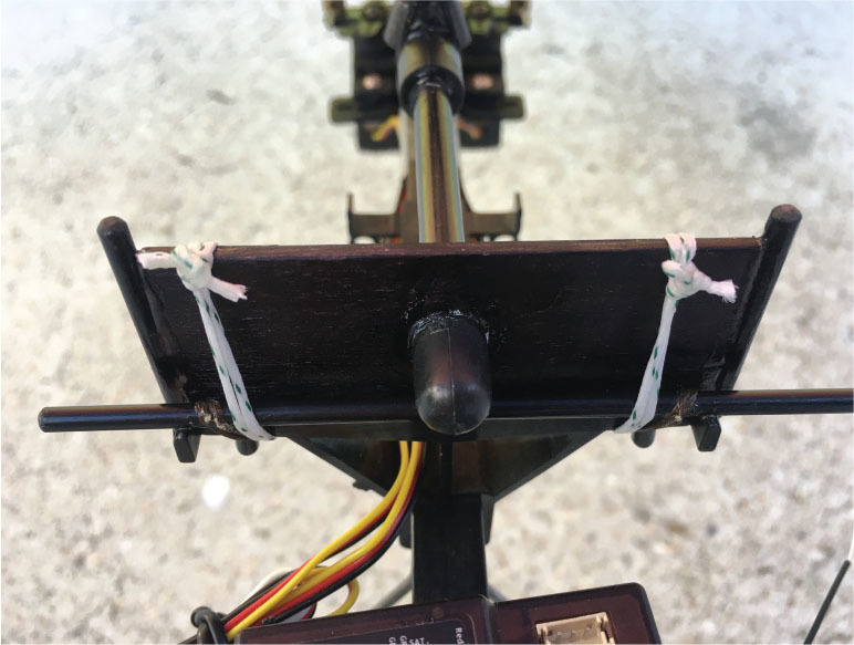 Aerial view of a model airplane tail assembly with wires and straps.