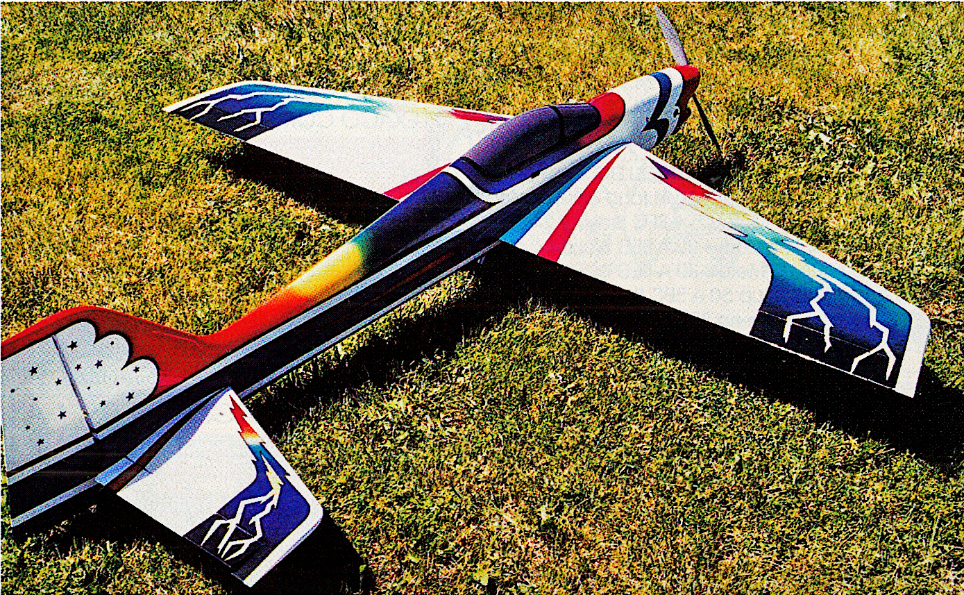 Colorful model airplane on grass with geometric patterns.