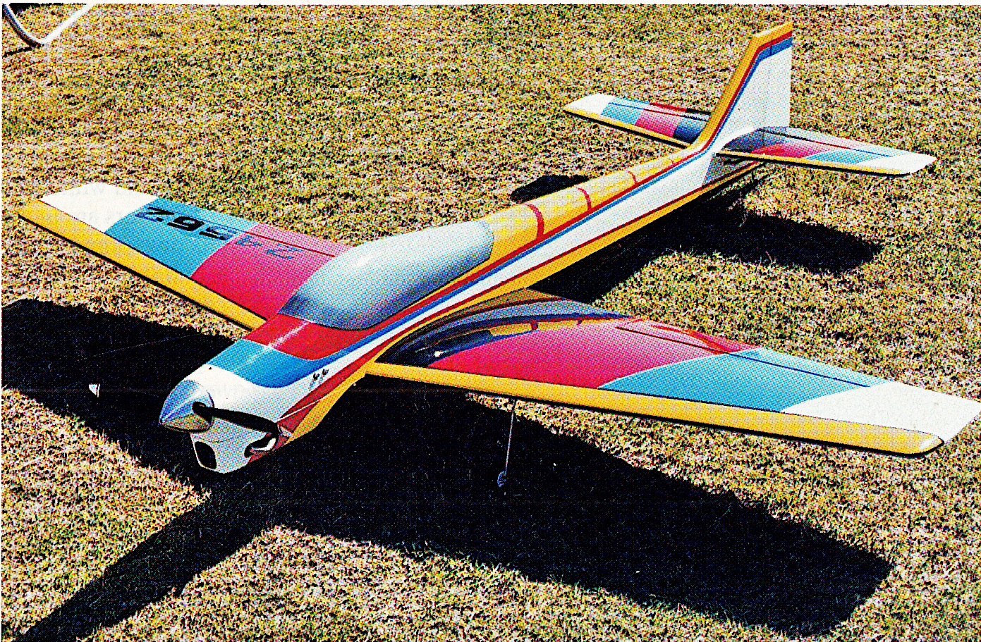 Colorful remote-controlled airplane on grass.