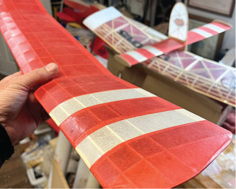 Model airplane with red and white striped wings in a workshop.