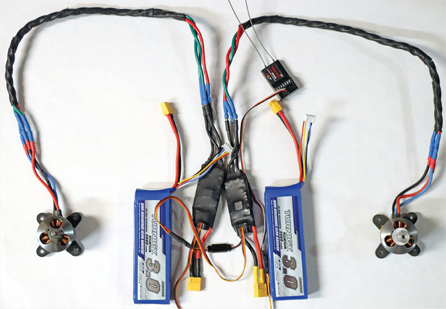 Drone wiring setup with motors and two blue batteries.