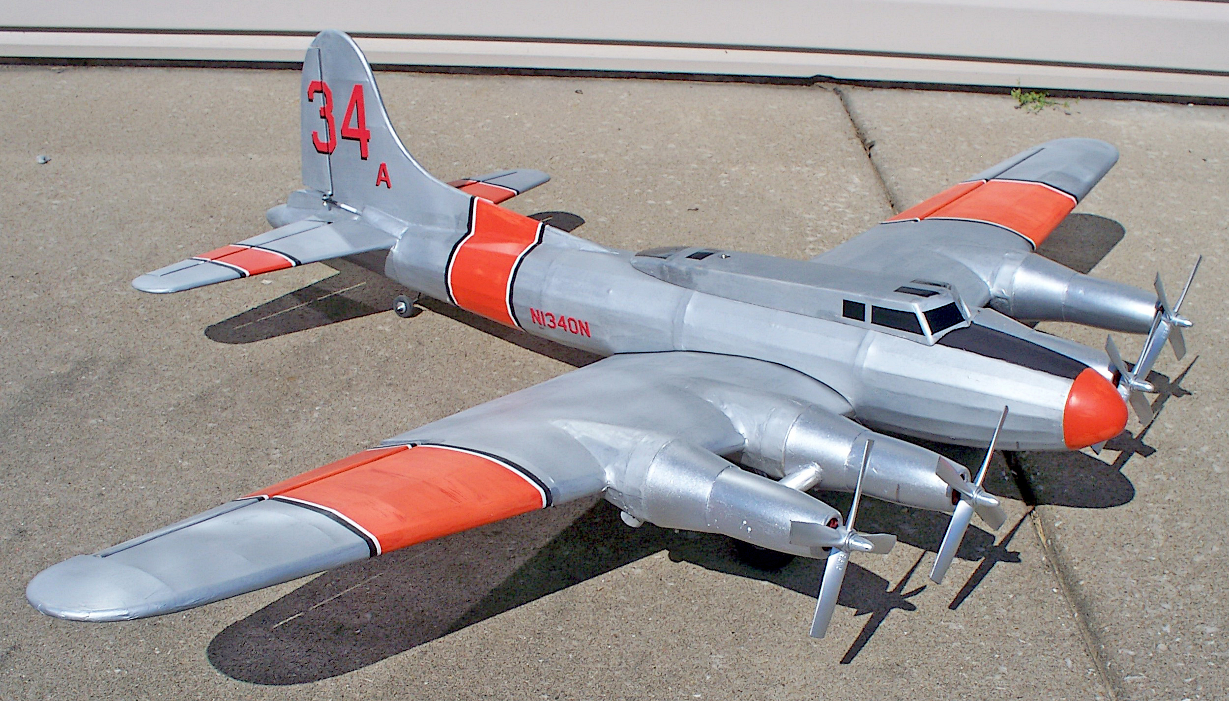 Silver and orange propeller airplane on a concrete surface.