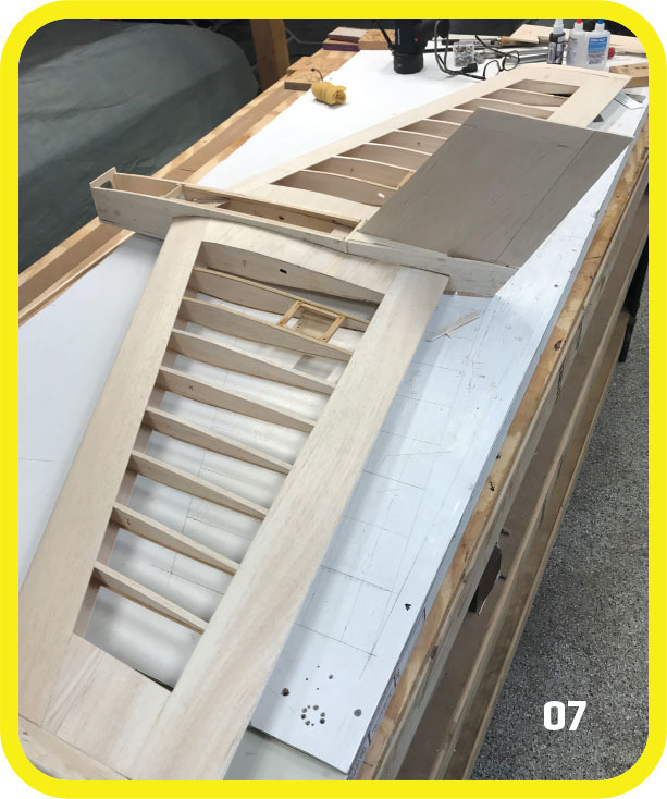 Wooden craft project on a workshop table, with slats and a draft paper.