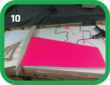 Bright pink triangle on a workbench with wires and tools. Number 10 at top left.
