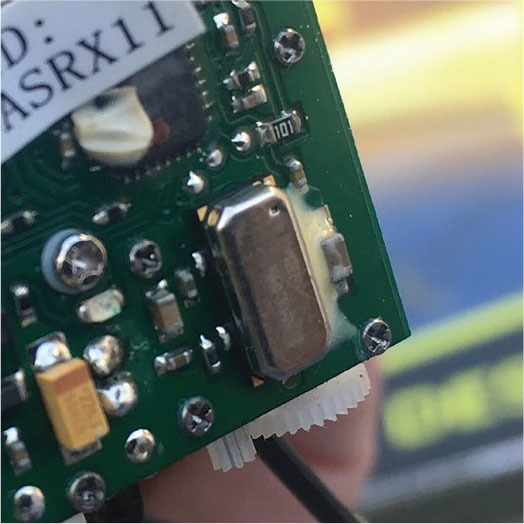 Close-up of a green circuit board with a metal component and visible text "ASRX11".