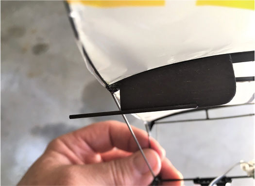 Hand holding a model aircraft wing against a gray background.