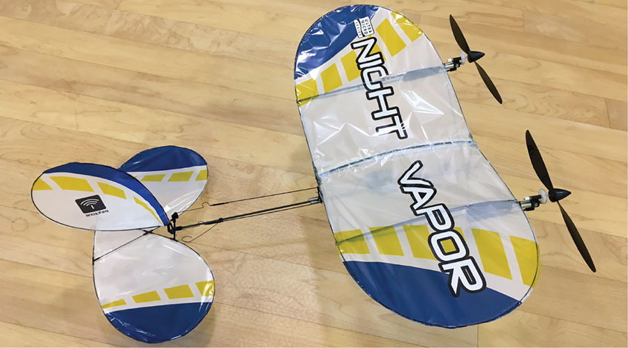 Toy airplane with "Night Vapor" text on wings, resting on wooden floor.