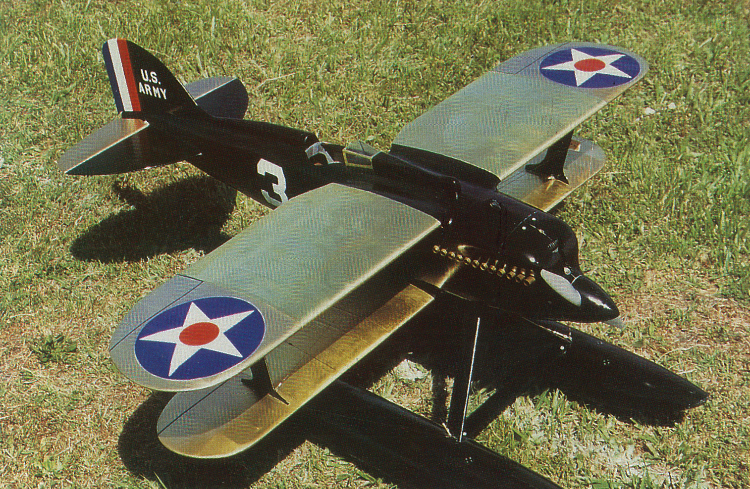 Toy military biplane with star insignia on green grass.