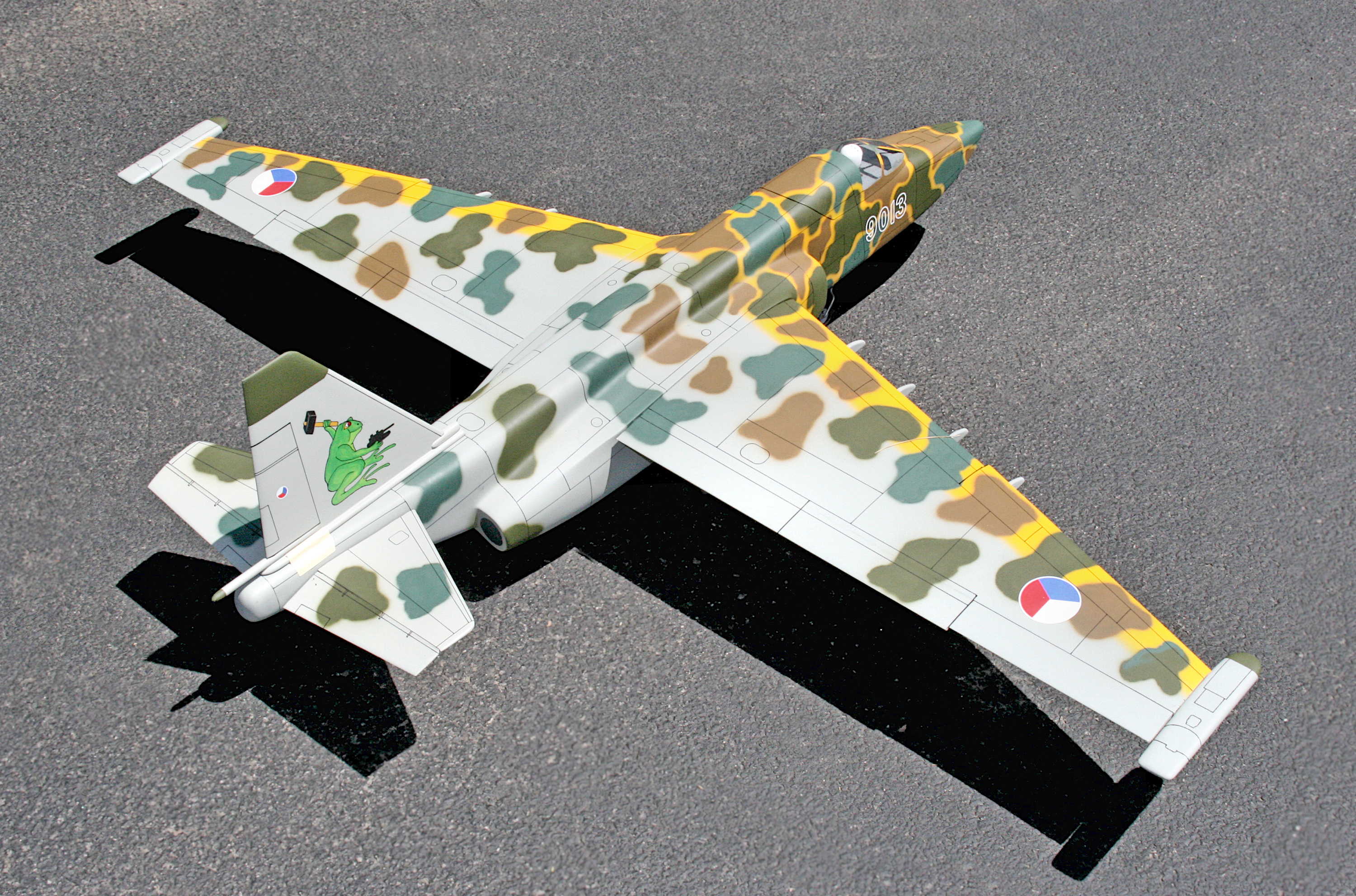 Camouflage model airplane on a gray surface.