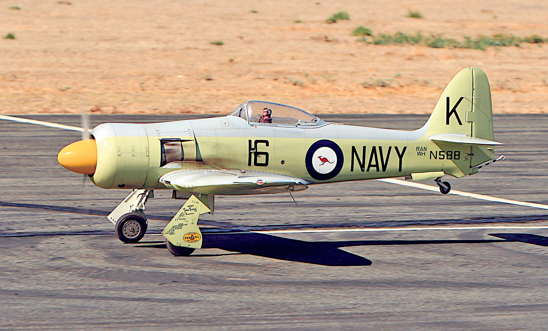 Green vintage Navy plane on runway, marked "16" and "K".