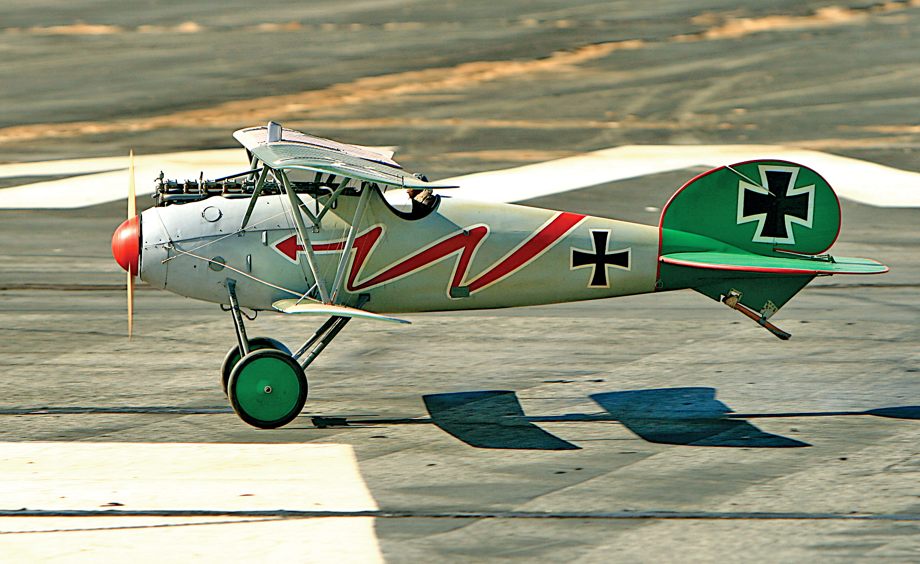 Historic biplane with German markings on a runway.