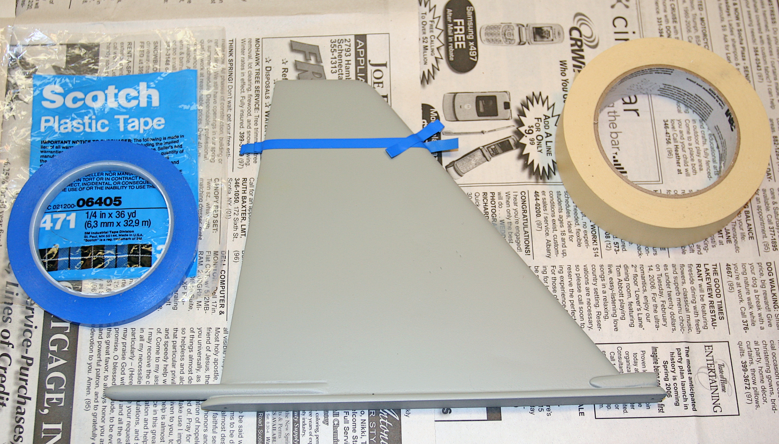 Blue and beige tape rolls on newspaper with a gray plastic part in the center.