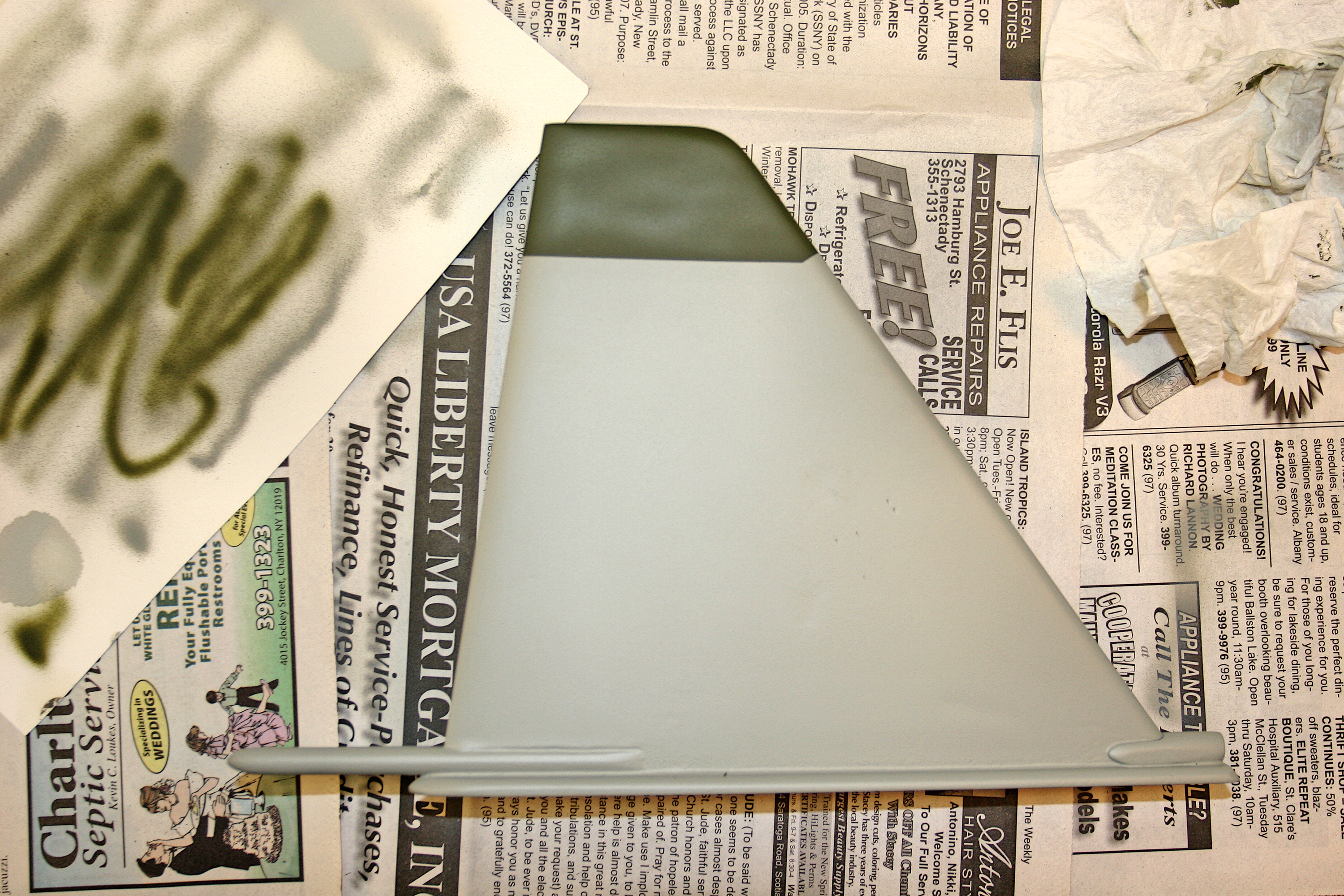 Gray triangular object on newspaper with painted green tip.