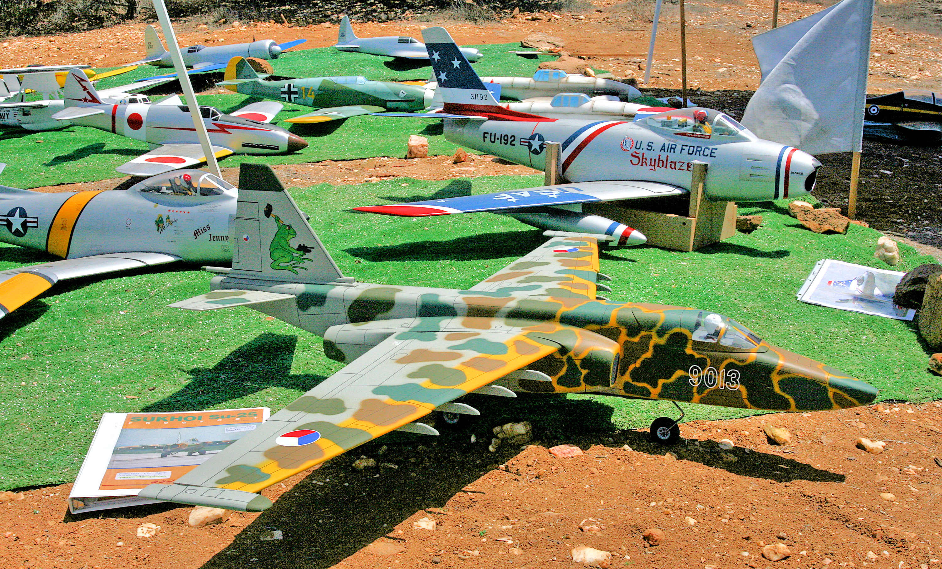 Model aircraft displayed on grass, various types and colors.