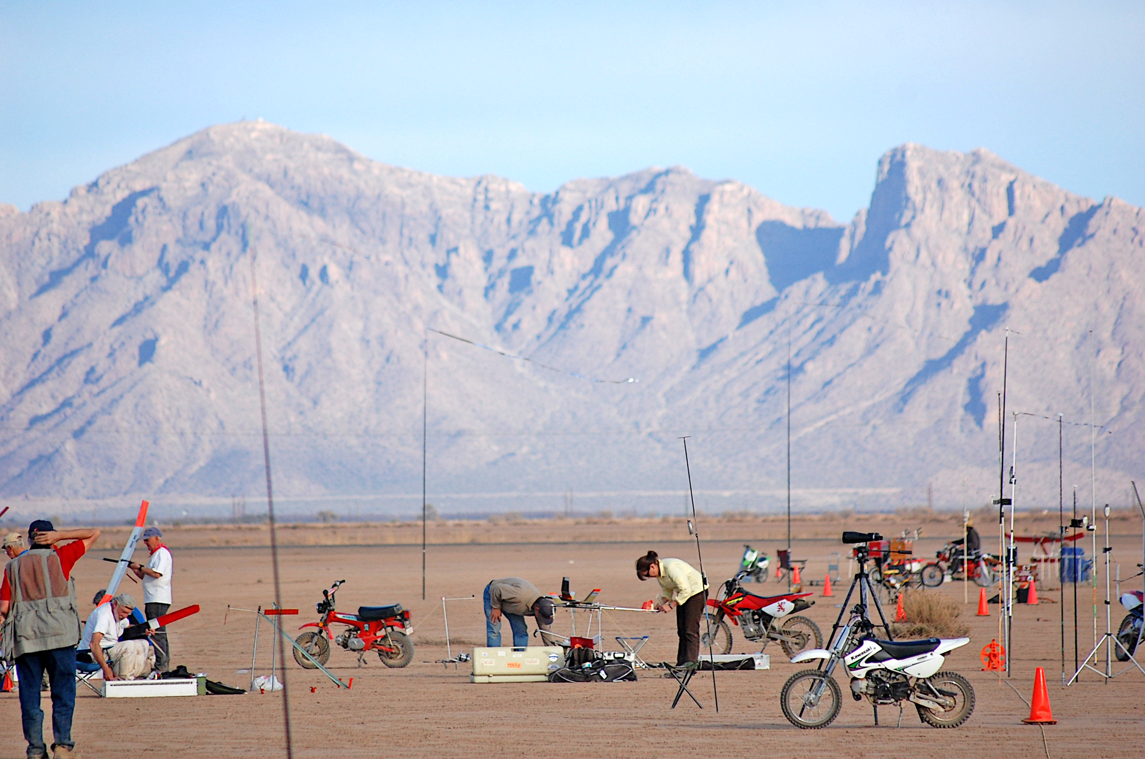 Desert motorcycle gathering with mountains in background.