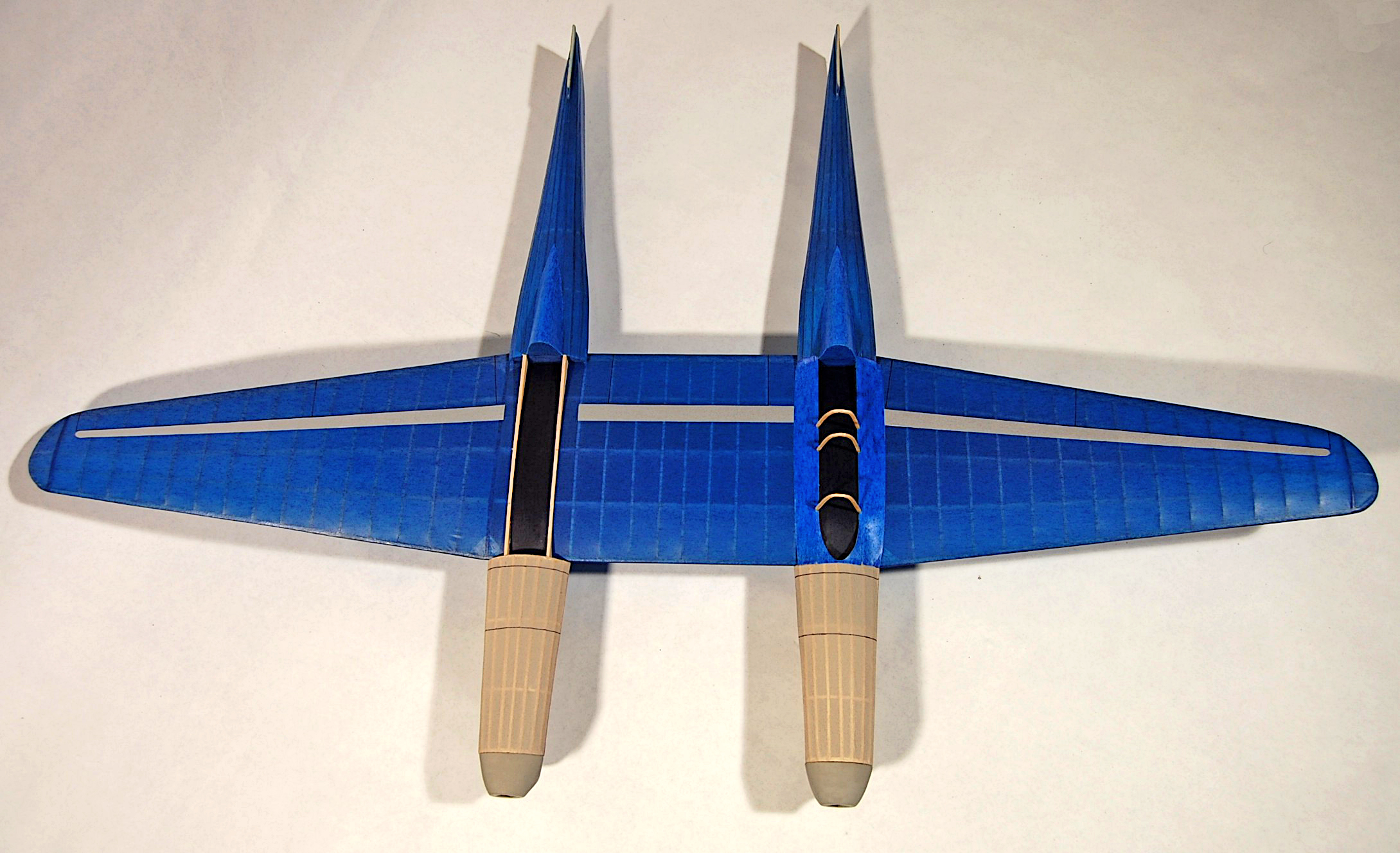 Blue toy plane with twin tail fins and beige landing gear on white background.