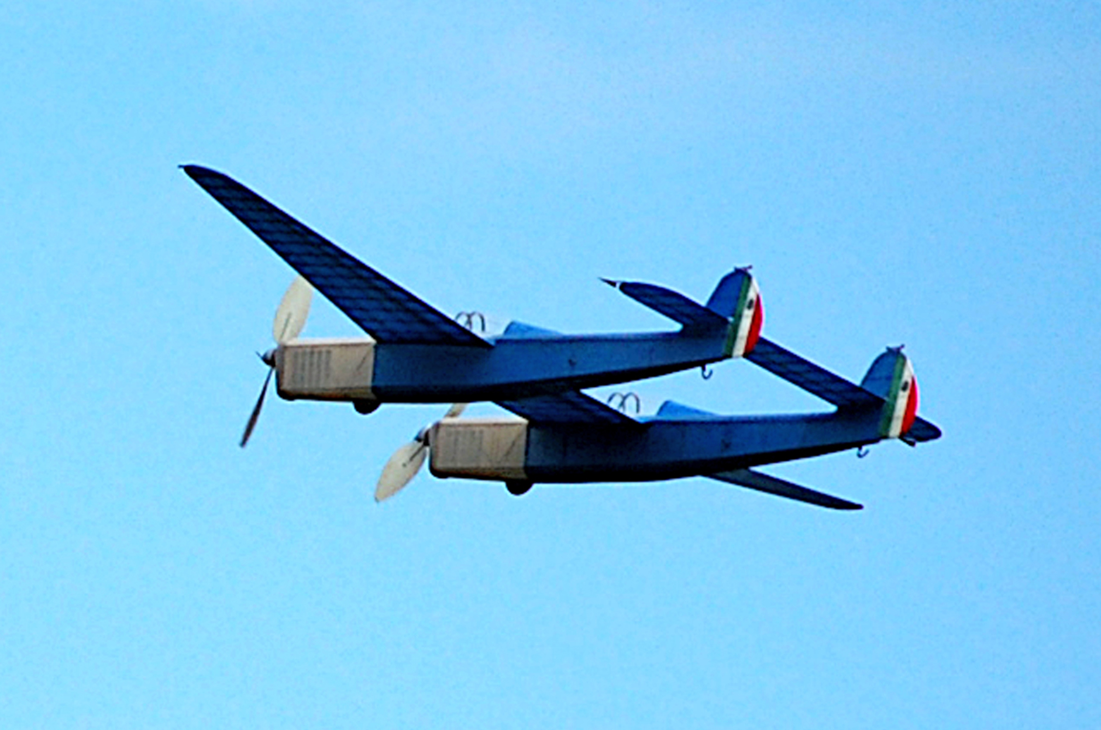 Twin-fuselage blue airplane flying in a clear sky.
