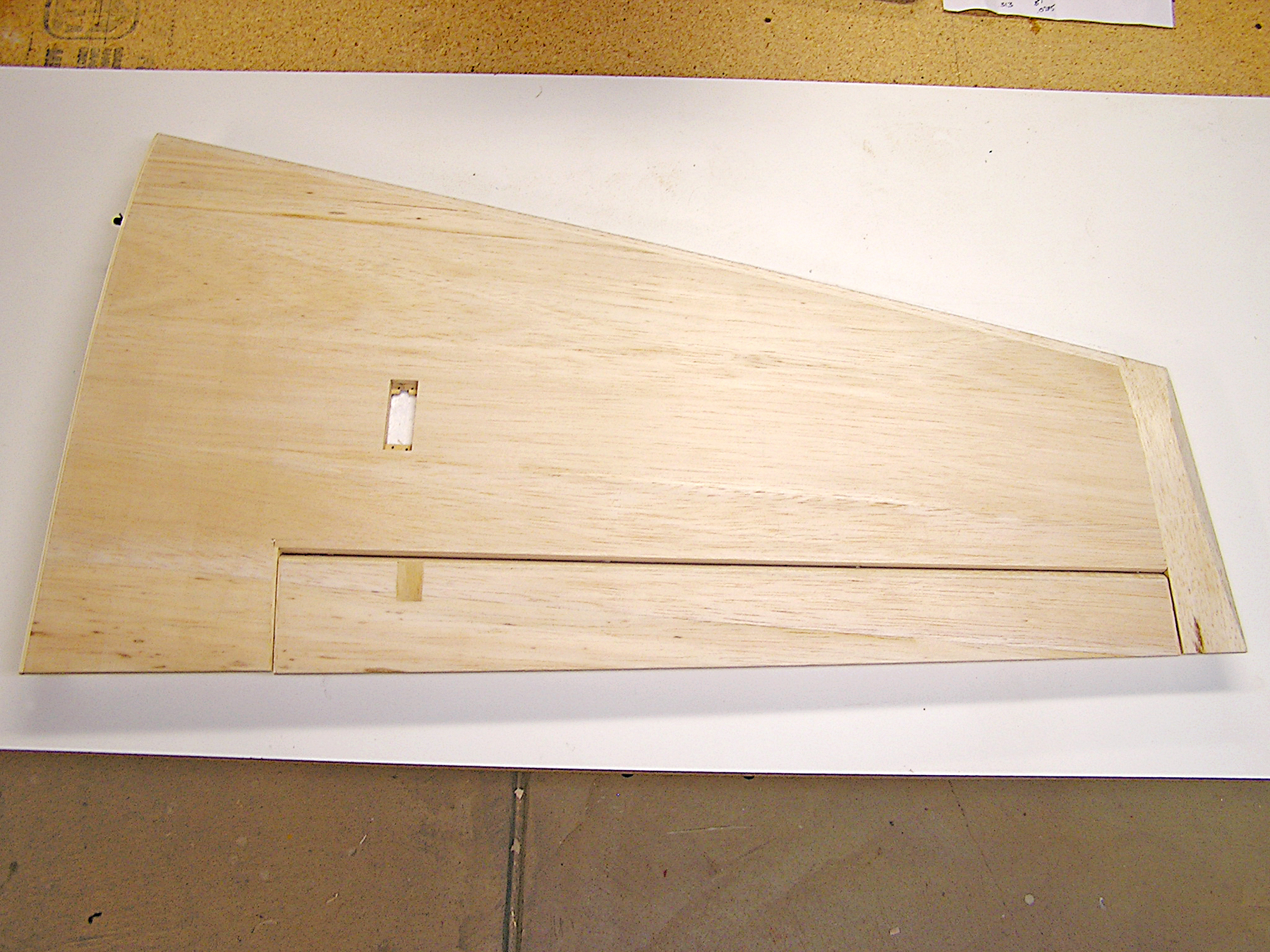 Wooden wing panel with rectangular cutouts, laid on a white table.