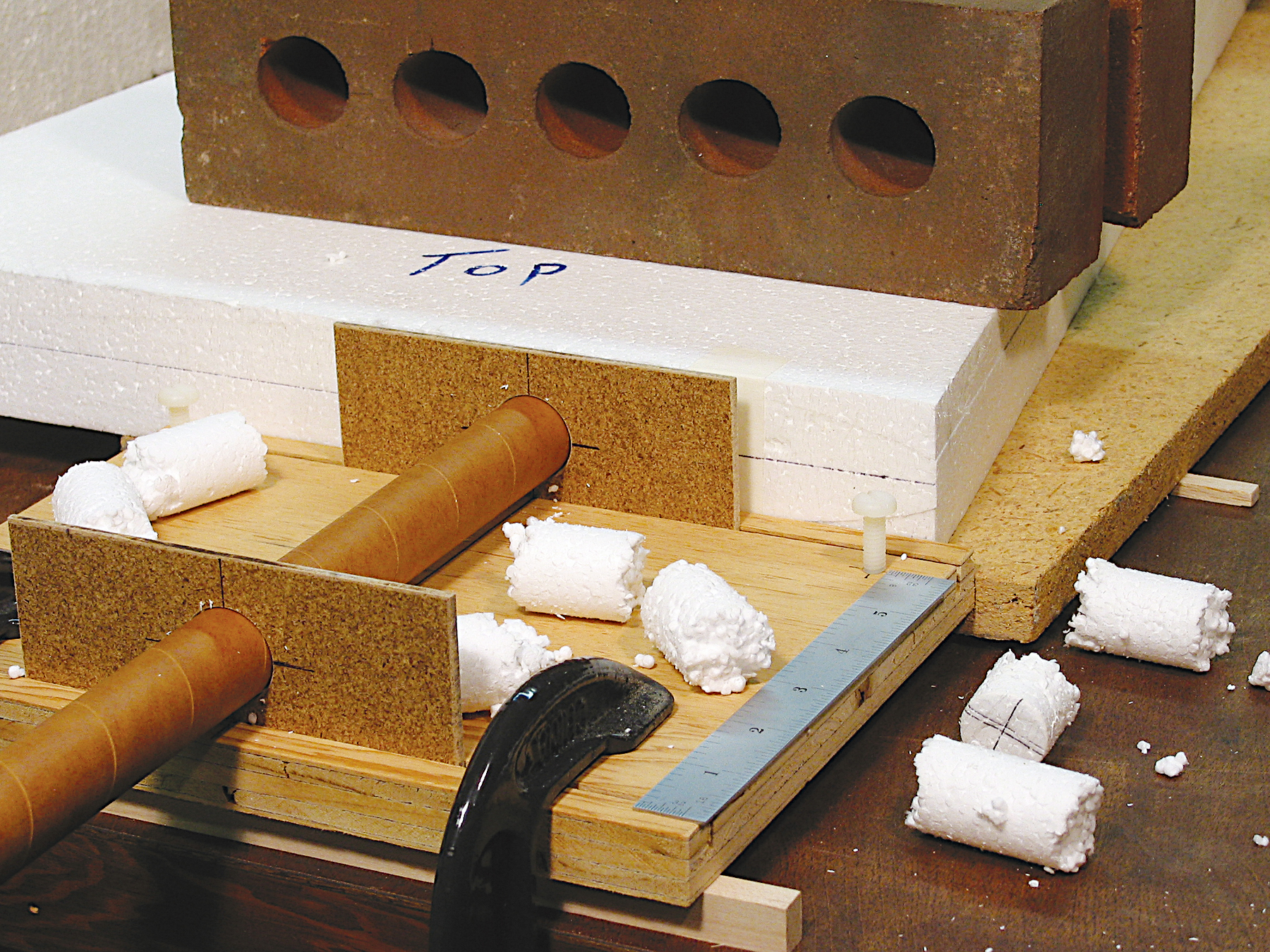 Foam cylinders on a wooden contraption under a heavy block.